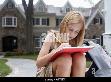 Girl (10-11) doing homework près de house, Chatham, New Jersey, USA Banque D'Images