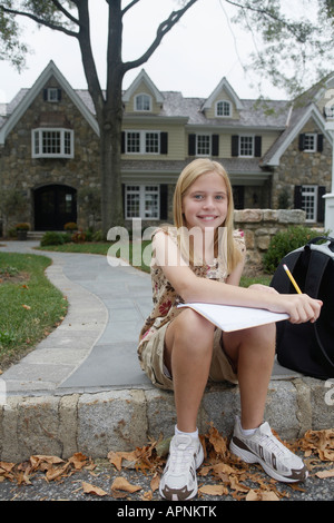 Girl (10-11) doing homework près de house, Chatham, New Jersey, USA Banque D'Images