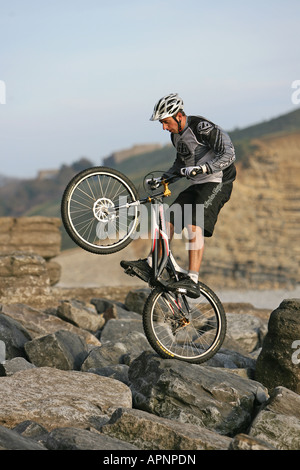 Un vélo de montagne perfoms une cascade sur les rochers. Banque D'Images