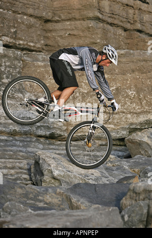 Un vélo de montagne perfoms une cascade sur les rochers. Banque D'Images