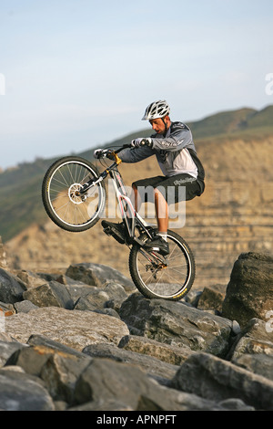 Un vélo de montagne perfoms une cascade sur les rochers. Banque D'Images