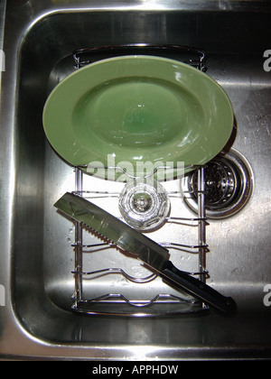 Scène nationale d'une plaque verte et d'un séchage dans un panier à vaisselle dans un évier de cuisine en acier inoxydable Banque D'Images