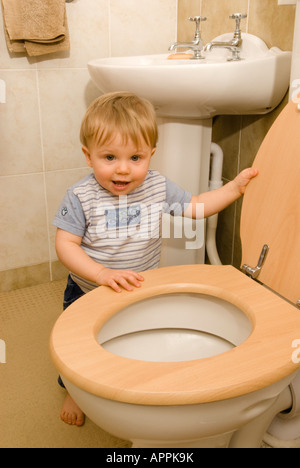 Bébé garçon de onze mois jouant avec des toilettes, siège de toilette relevé, non hygiénique Banque D'Images