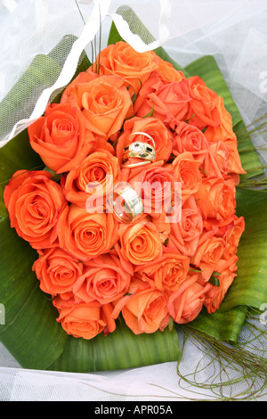 Les anneaux de mariage en orange bouquet de roses Banque D'Images