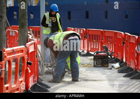 Builder se montrant bum crack l'aide d'une meuleuse pour couper les dalles de pavage de l'Irlande du Nord Belfast, Royaume-Uni Banque D'Images