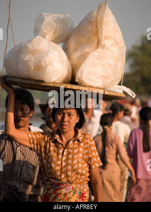 Une femme birmane avec une charge sur sa tête la traversée du pont U Bein près de Mandalay en Birmanie Banque D'Images