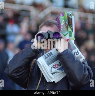 Homme avec des jumelles et l'après course et la race à la carte courses Sandown Park Banque D'Images