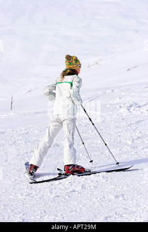 Young woman leaning on bâtons de ski Vertical image de femme mince attrayante en blanc et vert skisuit menant sur des bâtons de ski Banque D'Images