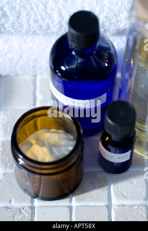 Les huiles essentielles en verre bleu les contenants remplis d'huiles bio d'herbes séchées, sel de mer, tourné avec une serviette en coton blanc Banque D'Images