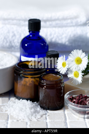 Les huiles essentielles en verre bleu les contenants remplis d'huiles bio d'herbes séchées, sel de mer, tourné avec une serviette en coton blanc Banque D'Images