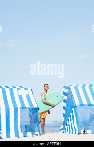 Hispanic man holding boogie board at beach Banque D'Images