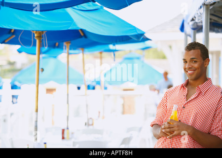 Hispanic man with drink at beach Banque D'Images