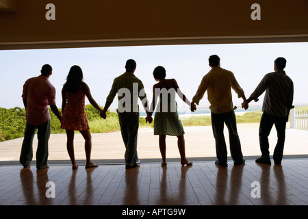 Silhouette of friends holding hands at beach resort Banque D'Images