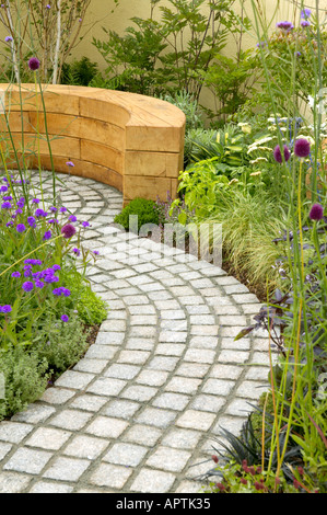 Flower Show Tatton chemin de galets incurvée avec banc en bois planté de hosta achillea et diverses graminées Banque D'Images