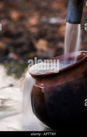 Remplissage d'un Indian Clay pot avec de l'eau propre et fraîche à une pompe à eau à main dans la campagne indienne. L'Andhra Pradesh, Inde Banque D'Images