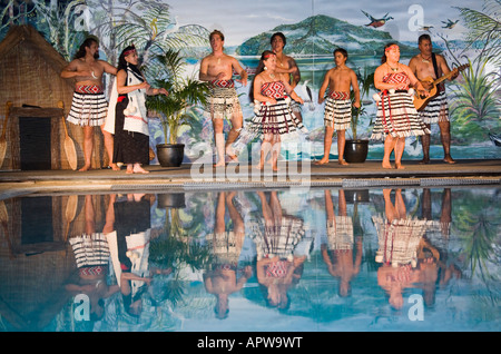 Les personnes qui font des chants et danses Maori traditionnel spectacle sur scène reflète dans l'eau de piscine Nouvelle Zélande Banque D'Images