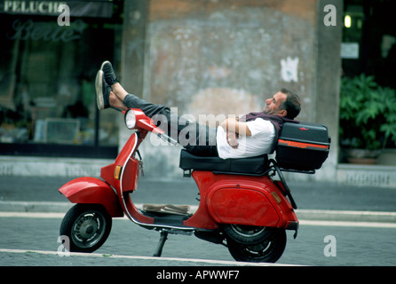 Europe Italie Rome un jeune homme prend une sieste sur son motorscooter rouge à la Piazza Navona Banque D'Images