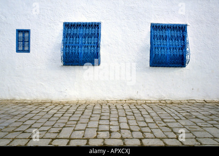 Trottoir en Sidi Bou Said montrant pavage et trois fenêtres bleues Banque D'Images