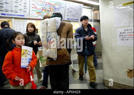 Sans-abri, Tokyo, Japon, vieil homme solitaire porte son sommeil en carton fort sur son dos, le plastique protège son carton de la pluie, il Banque D'Images