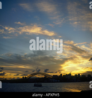 Fiery spectaculaire coucher de soleil de nuages striés orange avec Sydney Harbour Bridge et sur les toits de la ville en silhouette Sydney Australie Banque D'Images