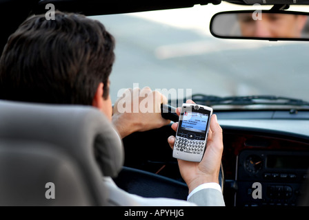 Contrôle de l'homme d'affaires téléphone dans sa voiture avec un reflet de lui dans le rétroviseur Banque D'Images
