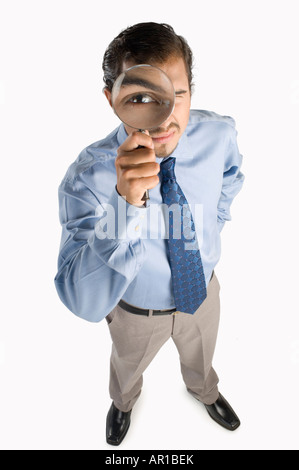 Jeune homme à la loupe à travers, portrait, elevated view Banque D'Images