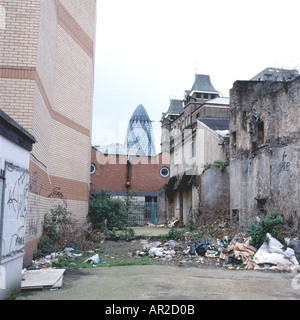 Vue sur le 30 St Mary Ax ou le bâtiment de gherkin depuis une allée de fond urbaine parsemée de détritus près de Brick Lane dans l'est de Londres Angleterre KATHY DEWITT Banque D'Images