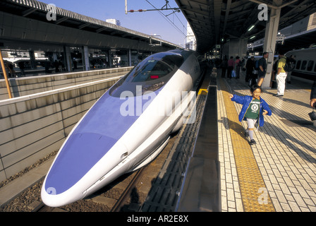 Garçon debout à côté d'un super-bullet train Shinkansen à la gare de Tokyo. Banque D'Images