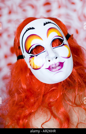 Portrai d'une femme avec une perruque rouge et masque de carnaval Banque D'Images