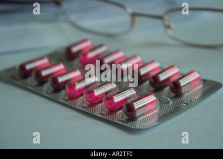Concept image montrant les comprimés médicinaux / comprimés / gélules, lunettes de lecture et fiche de renseignements à l'arrière-plan. Banque D'Images
