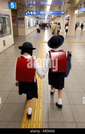 Deux jeunes écolières japonaise marcher dans une gare ferroviaire au Japon Banque D'Images