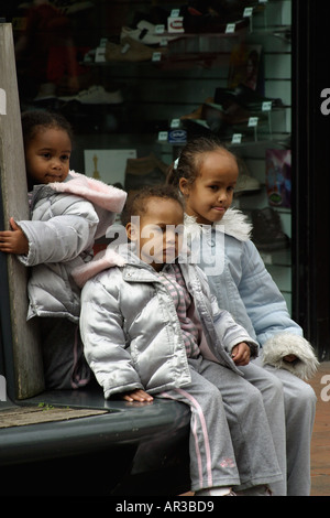 Trois jeunes filles de couleur assis regardant street artiste du spectacle Banque D'Images