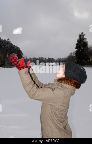 Woman throwing snowball dans l'air Banque D'Images