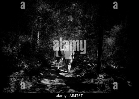 Un homme âgé ET UNE FEMME MARCHE À TRAVERS LA FORÊT SOMBRE Banque D'Images