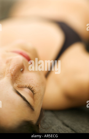 Selective focus close up of young woman lying on rock Banque D'Images