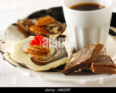 Blanc, lisse et marbré de chocolat au lait avec des fraises fraîches et de turbulences noix de pécan sur un plateau avec du café noir. Banque D'Images