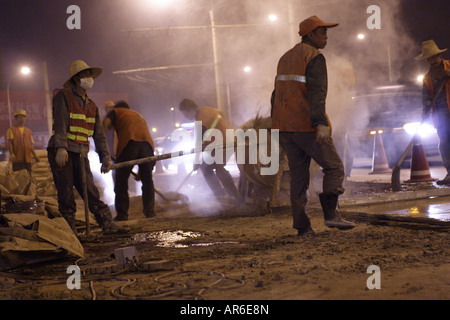 Ouvriers améliorer un revêtement routier tard dans la nuit dans la capitale chinoise, Pékin. Banque D'Images