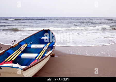 Barque tirée vers le haut sur la plage à marée montante comme Banque D'Images