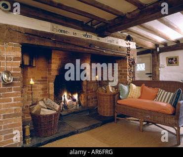 Paniers de sciage en cheminée Inglenook cottage avec poutres apparentes au salon avec canapé en rotin et tapis en sisal Banque D'Images