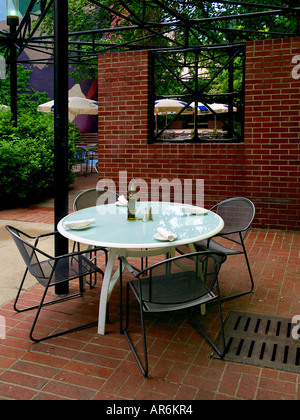 Table et chaises cyan dans une petite brique isolée plaza à côté d'un café en plein air. Banque D'Images