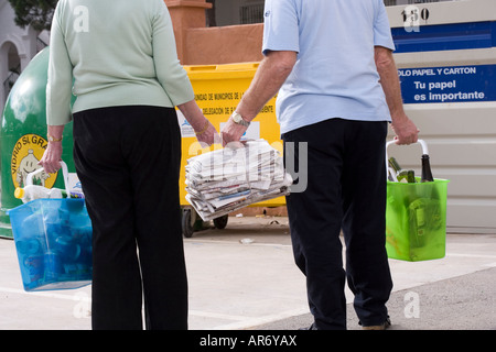 Senior couple transportant les journaux et les bouteilles en verre et en plastique vide à la corbeille Banque D'Images