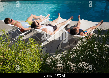 Les hommes de vous détendre dans les chaises de parterre à côté piscine Banque D'Images