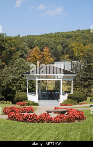 Gazebo blanc et rouge des fleurs dans un cadre de montagne d'été romantique. Banque D'Images