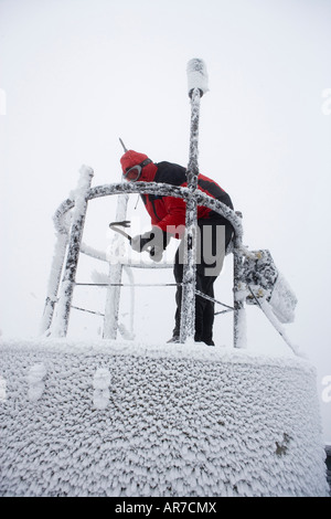 Un accompagnateur dissipe la glace des instruments à l'Observatoire du Mont Washington Banque D'Images