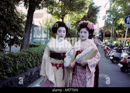 Long coup de deux apprenties geishas 'maikos' au travail à pied le long des rues de Kyoto au crépuscule. Banque D'Images