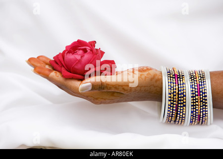 Indian girl with henna hands holding red rose Banque D'Images