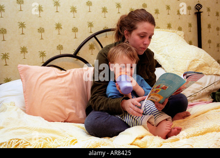 Les jeunes mères adolescentes la lecture à son fils à l'heure du coucher. Banque D'Images