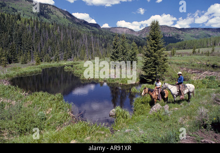 Deux cowboys cavaliers reste à un étang de castors et des barrages de castors dans les Flattops élevé dans les montagnes Rocheuses, dans le centre de Colorad Banque D'Images