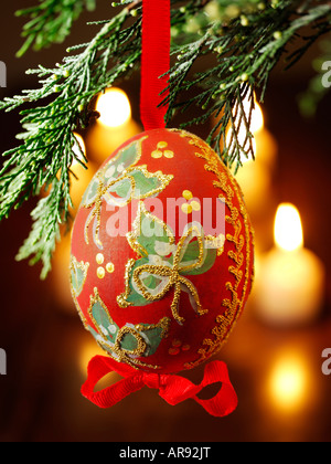 Boule de Noël traditionnelle à la décoration festive accrochée à un sapin de Noël avec lumières derrière Banque D'Images
