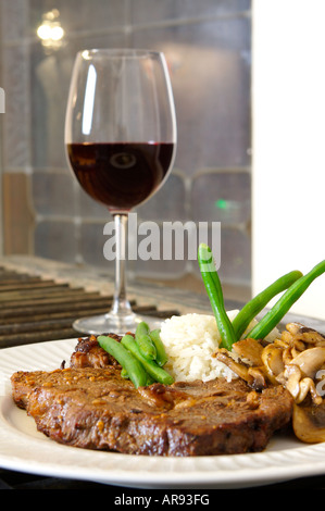 Ribeye cuit riz farine de haricots verts et de champignons close up avec du vin rouge hors focus shot d'un bas niveau prix pour le texte Banque D'Images